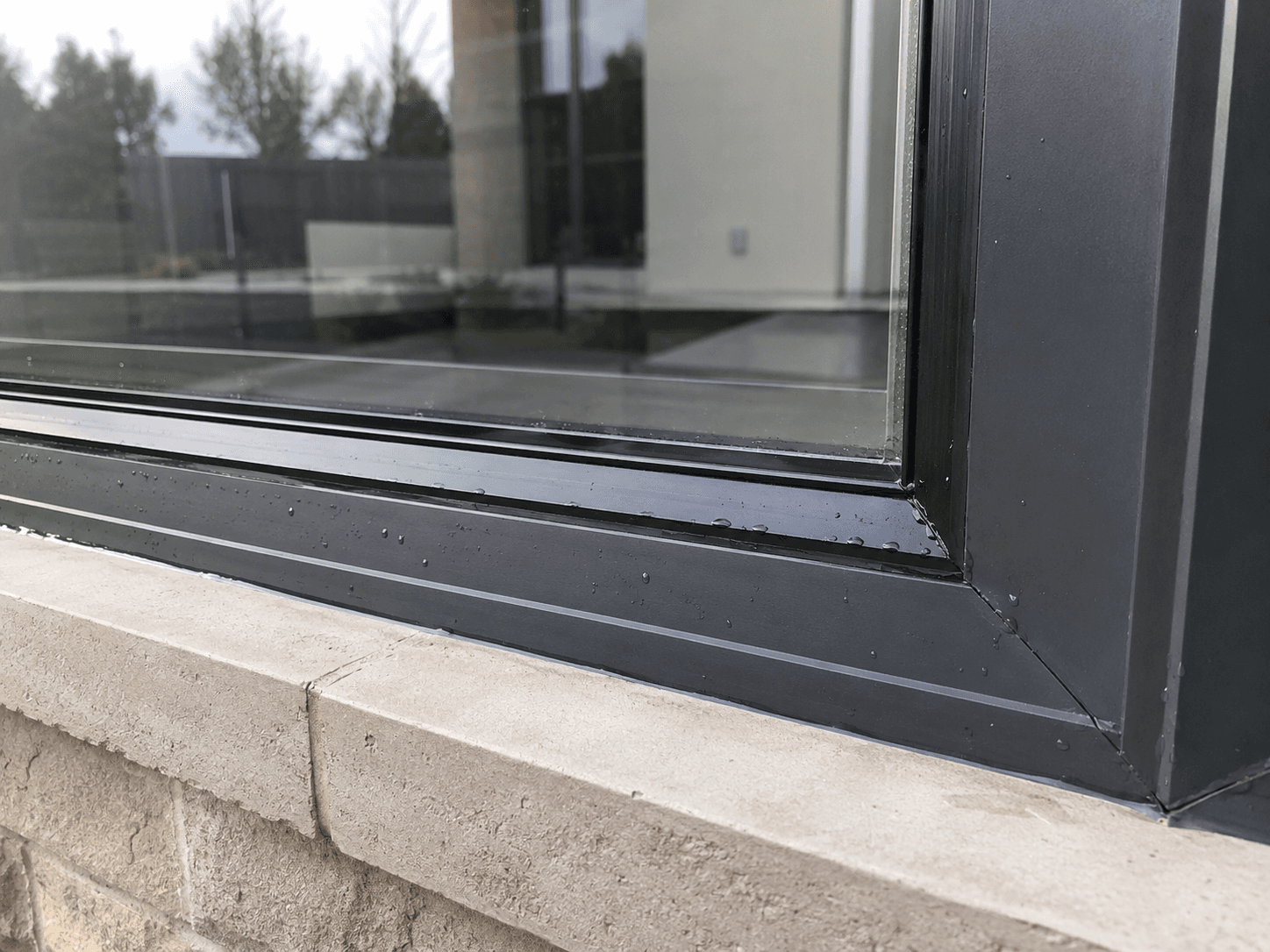 Close-up of a window frame and stone sill corner with water droplets after cleaning
