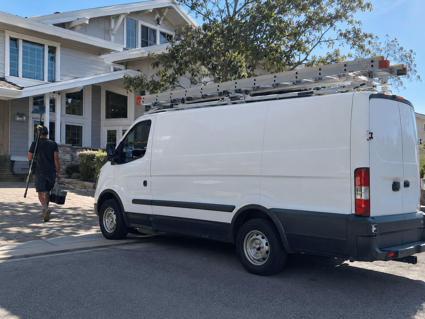 White cleaning service van with a ladder rack parked in a residential driveway
